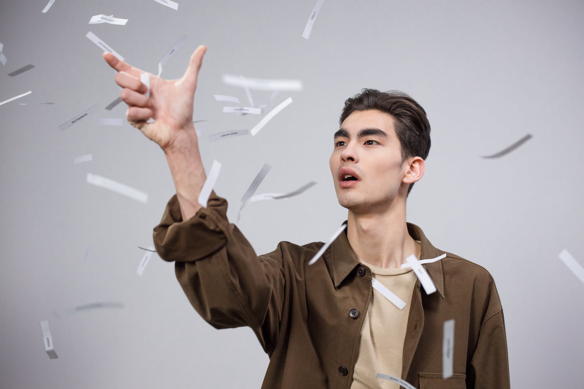 man in brown button up shirt catching papers in air