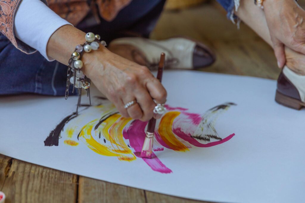 A woman artist painting abstract colorful strokes on paper with a brush, showcasing creativity.